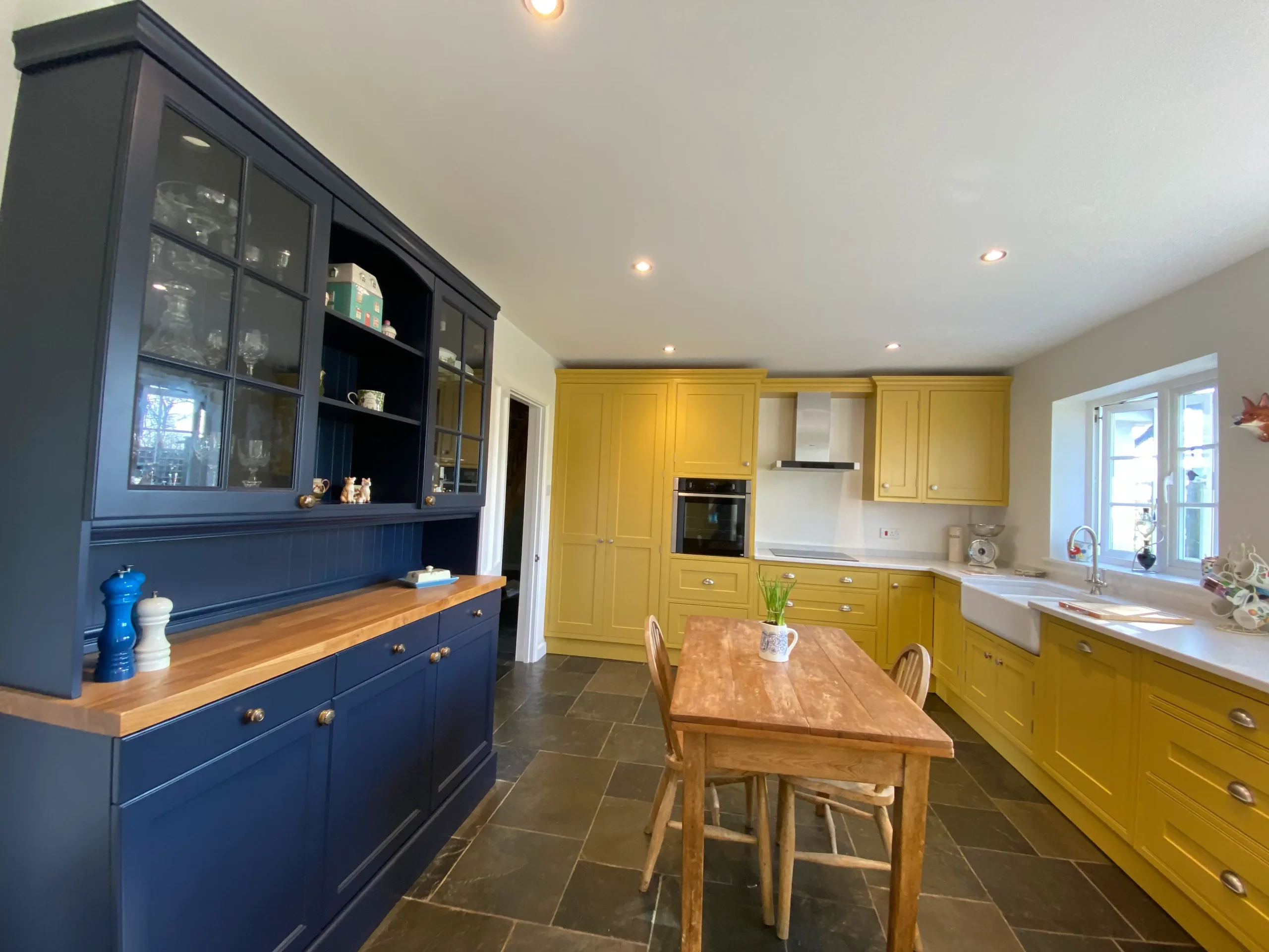 A bespoke joinery kitchen with yellow cabinets and a navy dresser.