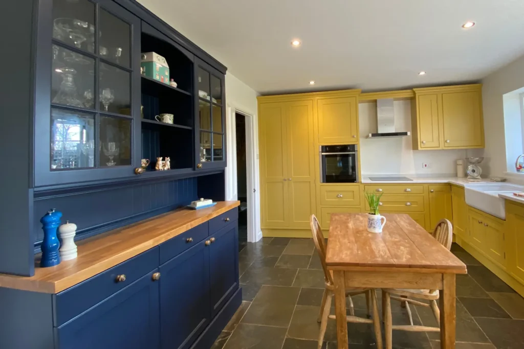 A bespoke joinery kitchen with yellow cabinets and a navy dresser.