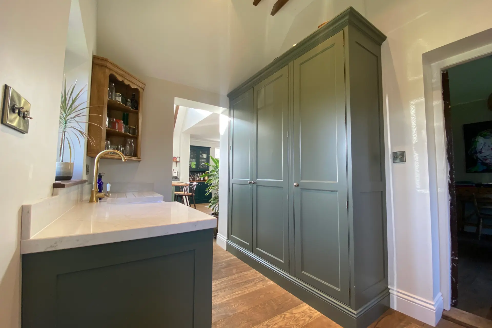 Floor to ceiling sage green kitchen cabinets in a utility room