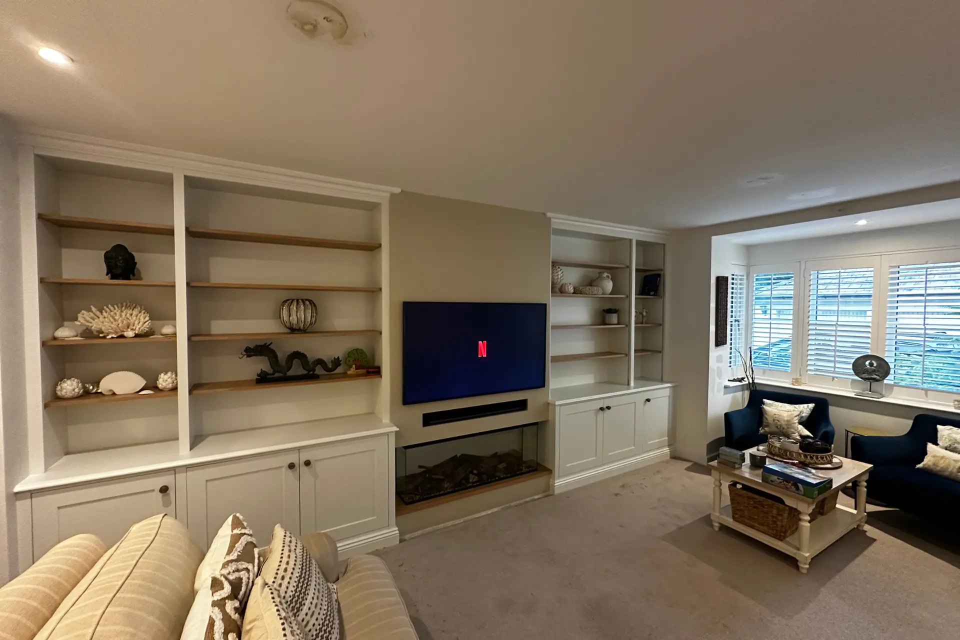 Cream shelving and cupboards home cinema and media wall in a lounge