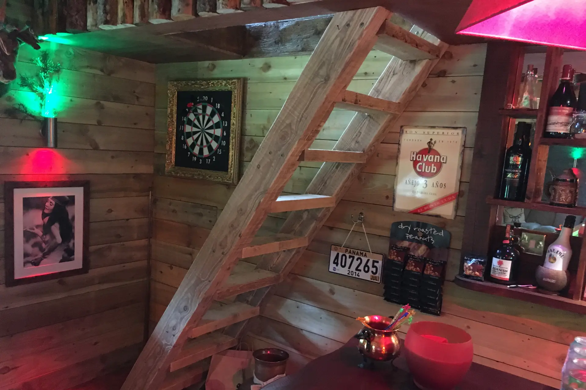 Man cave with a dart board and a ladder leading to an upstairs mezzanine