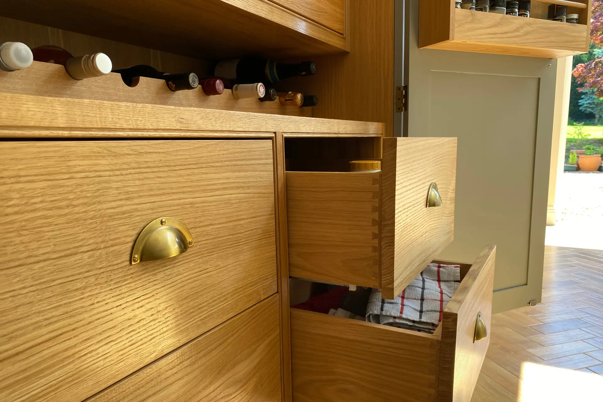 oak kitchen fitted drawers that have are open, with classic brass handles